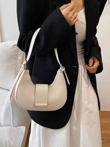 Minimalist cream crescent hobo bag with gold hardware shown on shoulder of a model