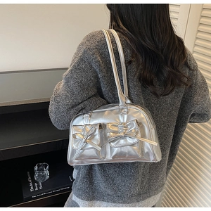 Detail view of metallic silver shoulder bag with bow decor and dual front pockets
