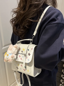 Sac à dos blanc en cuir avec motif étoile et breloque ours porté par un mannequin