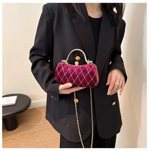 Detail of burgundy velvet clutch with diamond quilting, crystal studs and gold handle