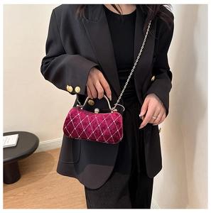 Burgundy velvet evening bag with diamond quilted pattern worn by a model