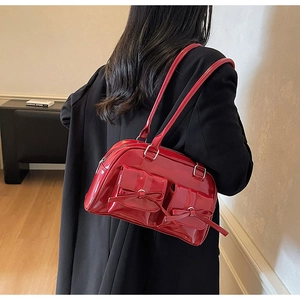 Detail of red patent leather shoulder bag with bow accents and double front flap pockets