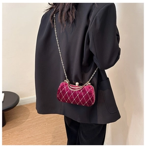 Close-up of burgundy velvet evening clutch bag with gold chain and diamond pattern details