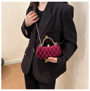 Detail of burgundy velvet evening bag with quilted rhinestone pattern and gold clasp