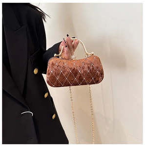 Detail of brown velvet evening clutch featuring diamond quilt pattern and gold metal handle