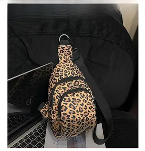 Vue détaillée du sac bandoulière léopard avec plusieurs poches zippées sur un canapé