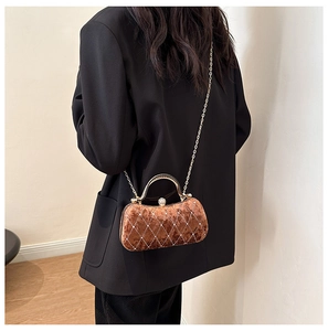 Detail of brown velvet evening bag with diamond lattice pattern and gold handle