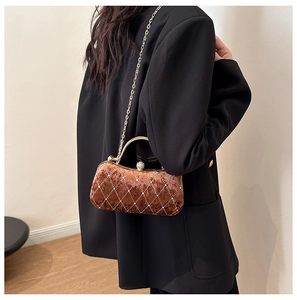 Detail of velvet dinner bag with diamond lattice pattern and golden metal handle