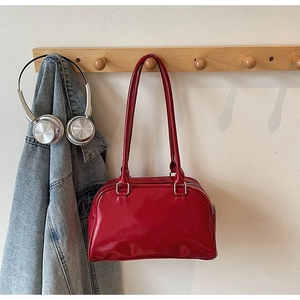 Glossy red patent leather bowling bag hanging on a wooden rack in a lifestyle setting