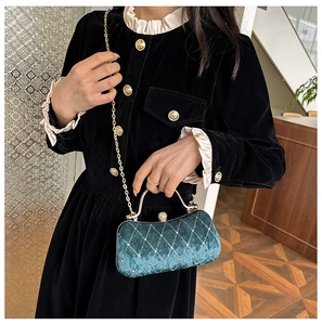 Detail of dark green velvet evening bag with gold chain and diamond studded lock
