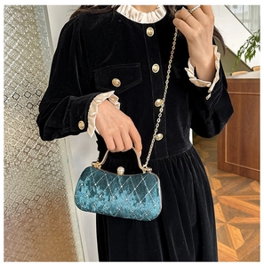 Close-up of velvet evening bag with diamond quilting and decorative gold handle