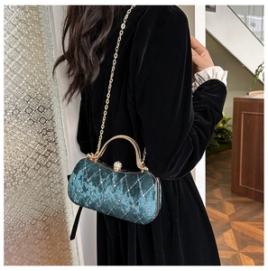 Detail of emerald velvet evening bag with diamond quilting and gold chain strap