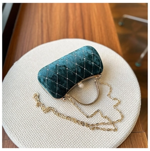 Macro detail of dark green velvet evening bag with diamond quilting and pearl clasp lock
