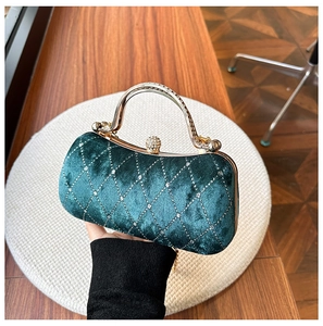 Close-up of dark green velvet evening bag featuring diamond lattice and crystal handle