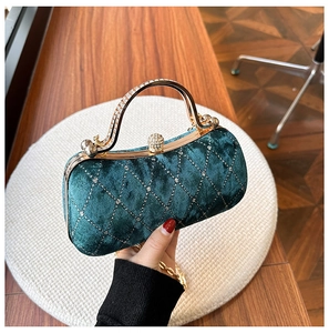Detail of dark green velvet evening bag with crystal diamond pattern and gold handle