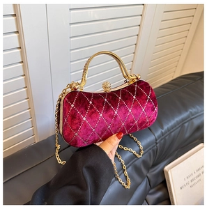 Close-up of luxury burgundy velvet clutch bag with diamond quilted pattern and metal handle