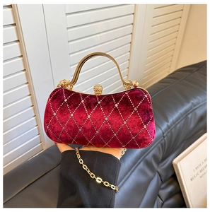 Detail of burgundy velvet clutch with diamond quilting and gold metal handle