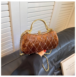 Detail of velvet evening bag featuring rhinestone quilted pattern and gold metal handle