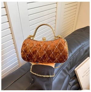 Detail of velvet evening bag with diamond quilting, crystal spherical lock, and gold handle