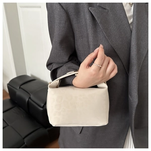 Detail der cremeweißen Lederhandtasche mit Tiermuster, getragen von einem Modell im Büro
