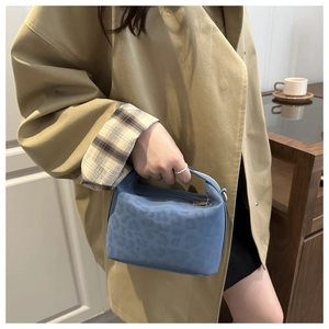 Details der blauen Handtasche mit Leopardenmuster, Metallreißverschluss und Samt