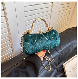Detail of dark green velvet evening bag with diamond lattice pattern and gold metal handle