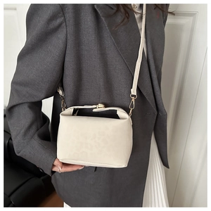 Detail of cream bucket bag with leopard embossed texture and golden metal buckle