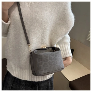Détail du sac bandoulière léopard avec boucle dorée et texture en daim doux