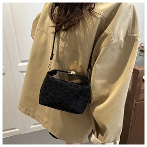 Detail of black leopard embossed handbag with elegant gold buckle and fine suede texture