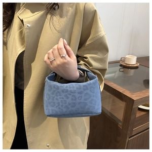 Close-up of light blue leopard-embossed suede handbag with elegant top handle detail