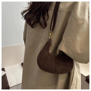 Detail of dark brown matte hobo bag with gold hardware worn with khaki trench coat