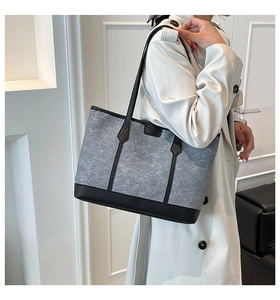 Detailed shoulder view of a large grey felt tote bag with black leather stitching details