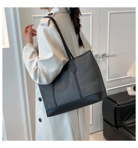 Side view of large matte black tote bag showing capacity and shoulder fit on model