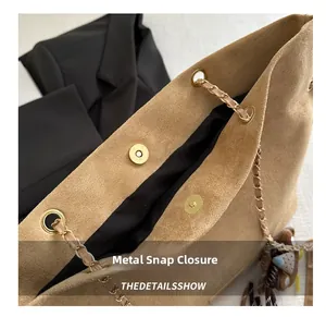 Detail of light brown suede tote bag featuring a gold hardware magnetic closure and chain