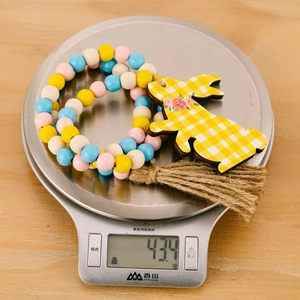 Close-up of Easter wooden bead garland with rabbit tag and tassel on a digital scale