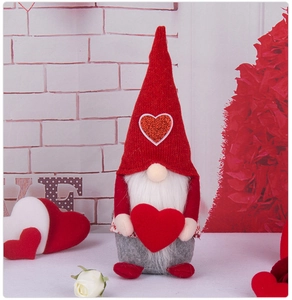 Close-up of Valentine gnome plush doll holding a red heart with white beard and knit hat