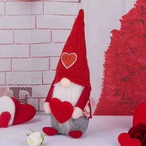 Handmade Valentine's Day gnome doll with red heart hat and plush beard on festive background