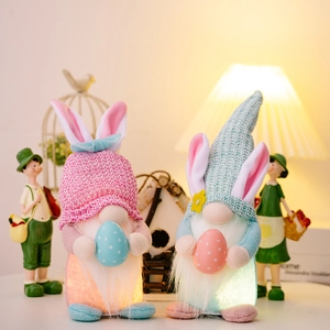 Gnomi di Pasqua luminosi con orecchie da coniglio e uova colorate in posa calda