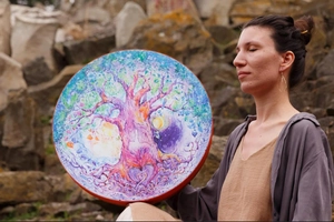 Artistic multi-colored Love Tree drum held by a person in a natural outdoor setting