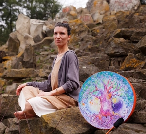 Artistic Shamanic Love Tree drum held by a person in a peaceful outdoor meditation setting