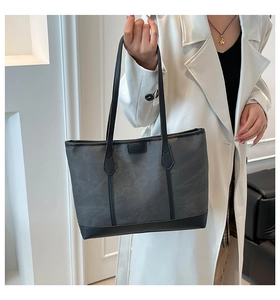 Detailed view of the large grey camo tote bag with black leather straps on a model