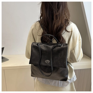 Close-up of black PU leather backpack featuring a vintage dark silver twist lock closure
