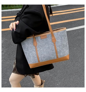 Detail of grey felt tote bag with brown leather handles on urban asphalt background