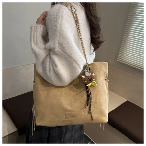 Dettaglio della borsa tote in pelle scamosciata con catena in metallo e ciondolo a orso