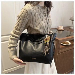 Dettaglio borsa shopper nera con scritta dorata e simpatico accessorio ciondolo orso