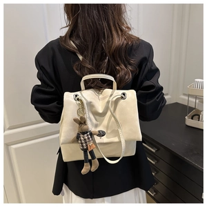 Detail of off-white faux leather backpack with a cute knit bunny doll charm and soft texture