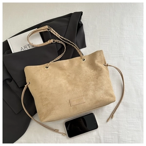 Dettaglio della borsa tote in pelle scamosciata kaki con manici intrecciati e punte in metallo
