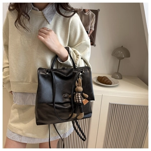 Detail of black leather backpack featuring a metal twist lock and cute bunny pendant