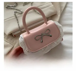 Detail of pink matte leather handbag with silver bow charm and white lace trim