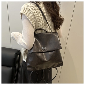 Detail of vintage dark brown faux leather backpack with metallic turn-lock and waxy finish